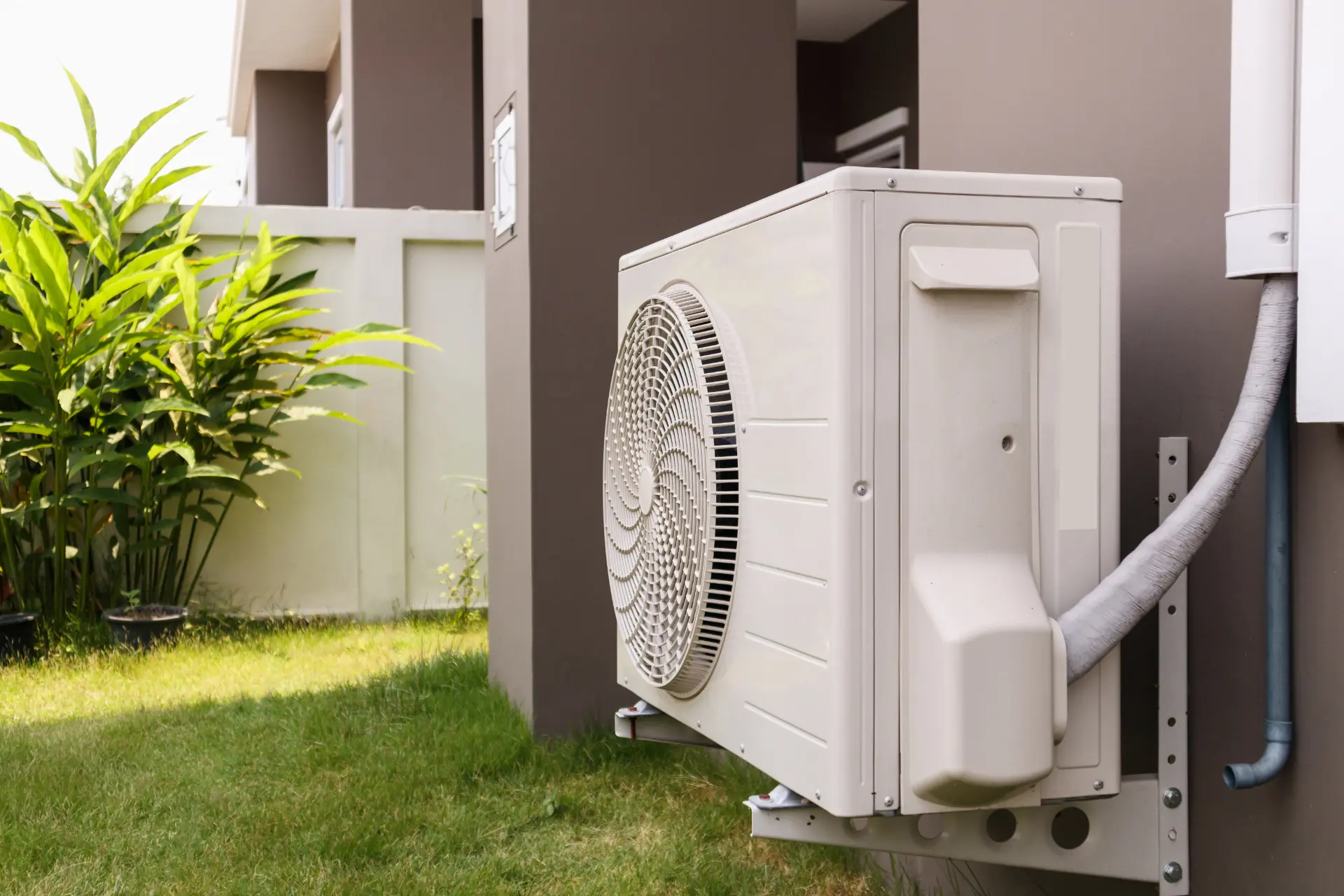 Air conditioning outdoor condenser unit wall-mounted outside a modern property